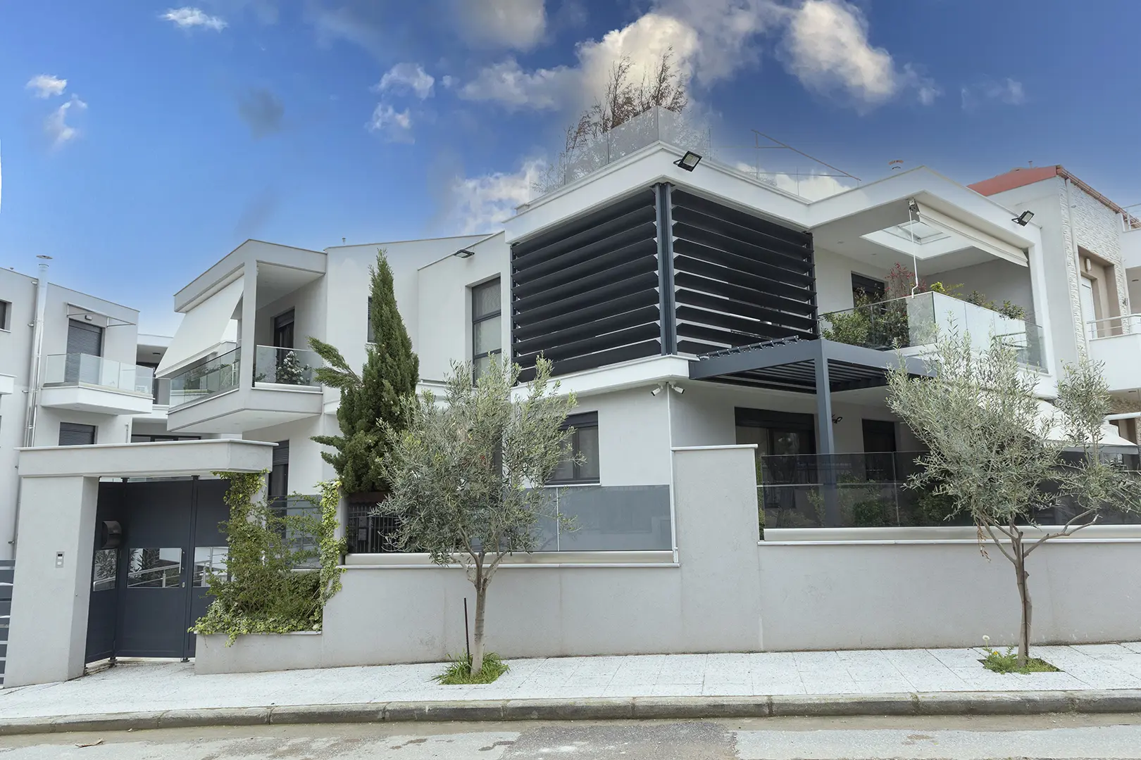 Modern apartment block with corner balconies overlooking Thessaloniki and the Thermaic Gulf at golden hour.