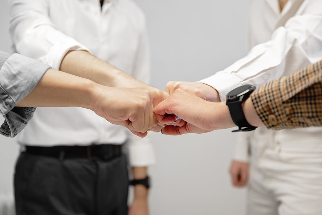 Close-up of diverse team members doing a fist bump indoors, symbolizing unity and teamwork.